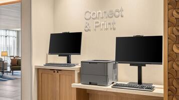 A reception desk with two monitors, a printer, and a keyboard.