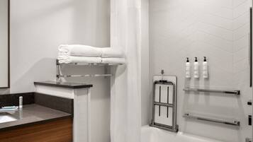 A modern bathroom with a shower, a sink with a mirror, and toiletries on a shelf.