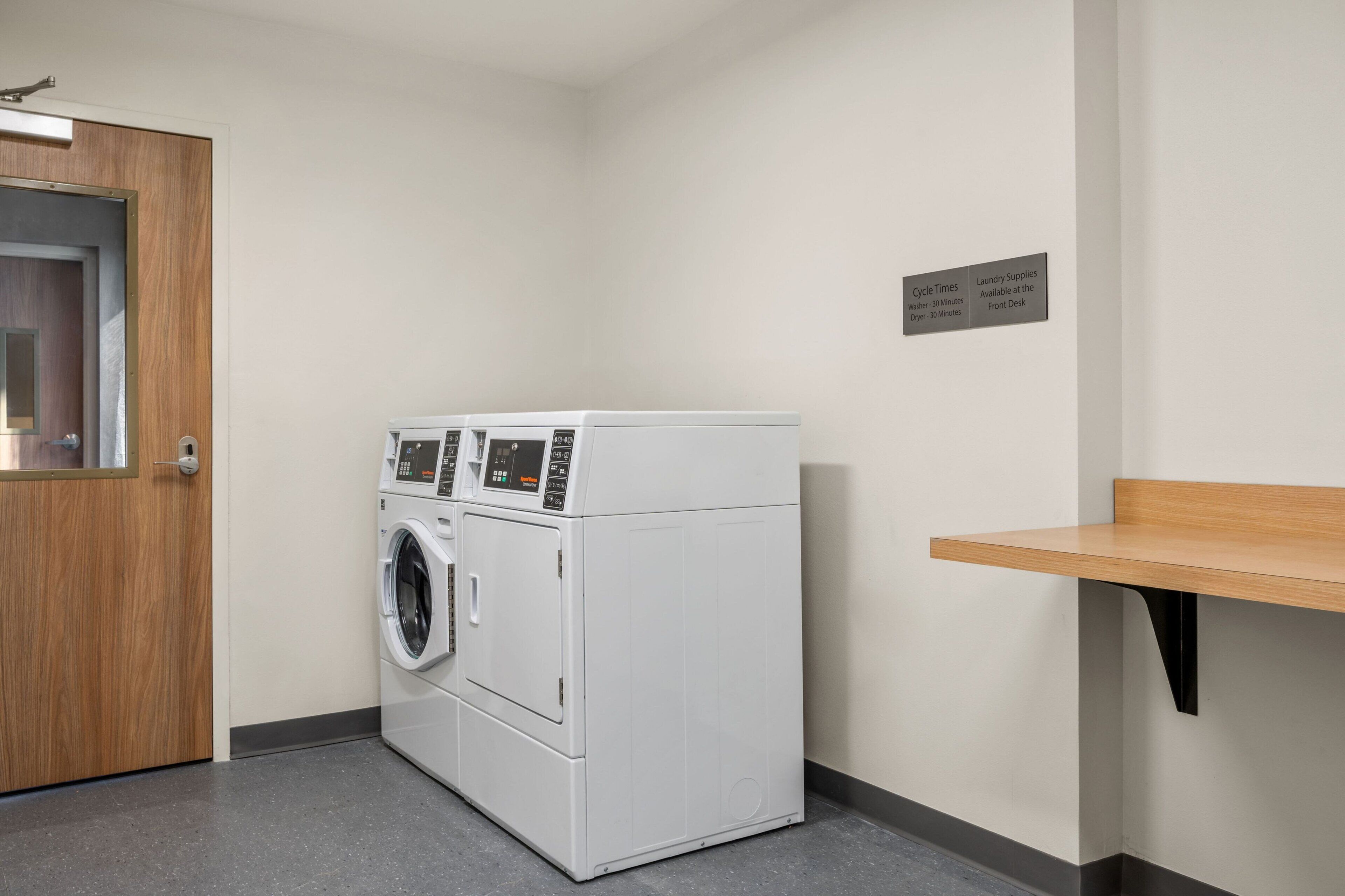 A laundry room with a front desk, a washing machine, and a dryer.