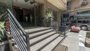 A hotel entrance with a staircase, a red chair, and a parked SUV. - Hibiscus Haven Suite  (Cairo)