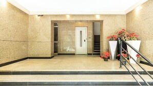 A lobby with a marble floor, a staircase, and a door leading to an elevator. - Hibiscus Haven Suite  (Cairo)
