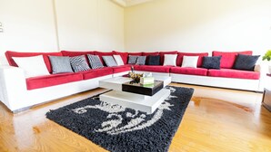 A modern living room with a red sectional sofa, a white coffee table, and a black rug. - Hibiscus Haven Suite  (Cairo)