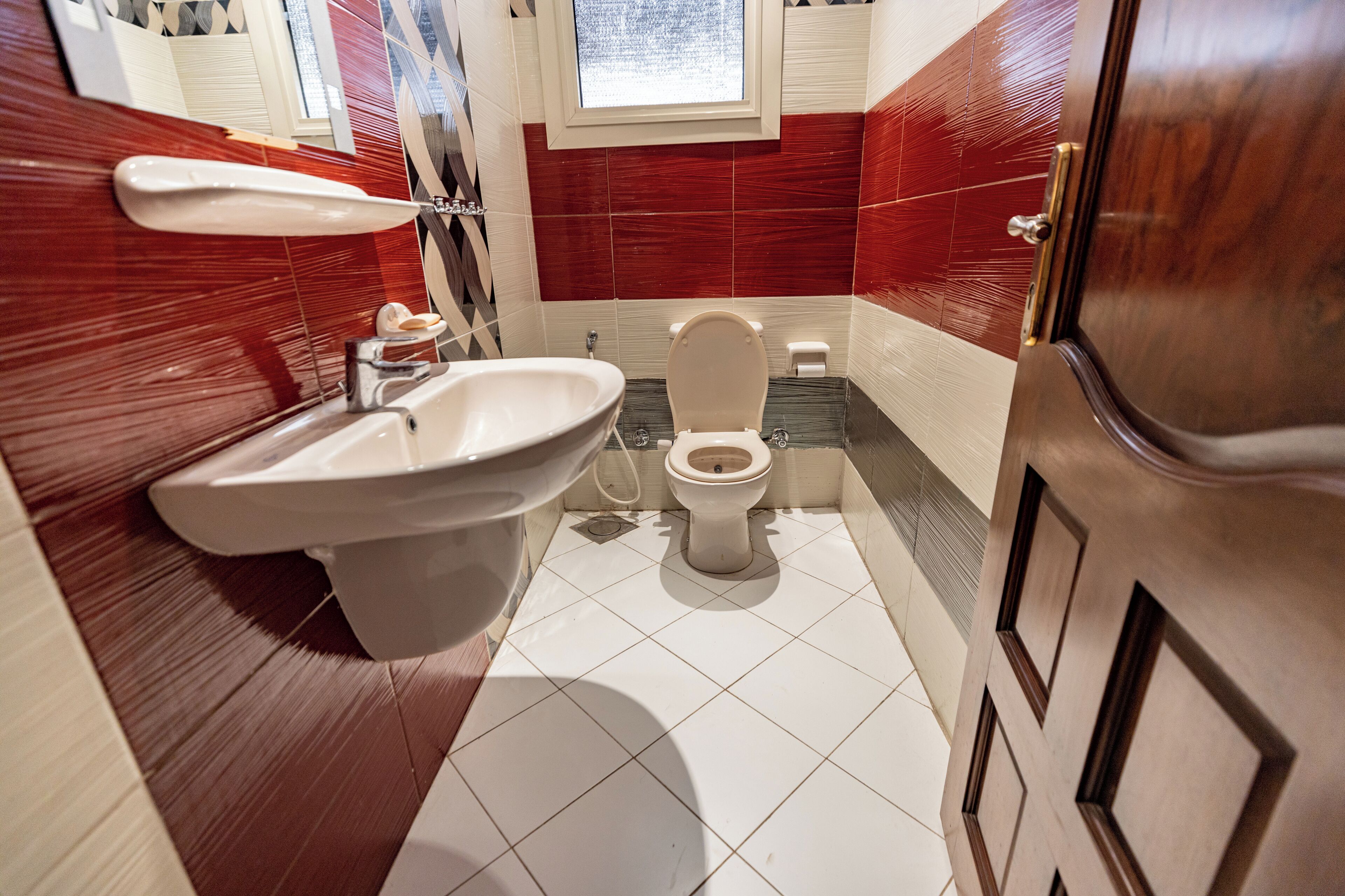 Une salle de bain avec un grand lavabo blanc, des toilettes et un miroir au-dessus du lavabo.