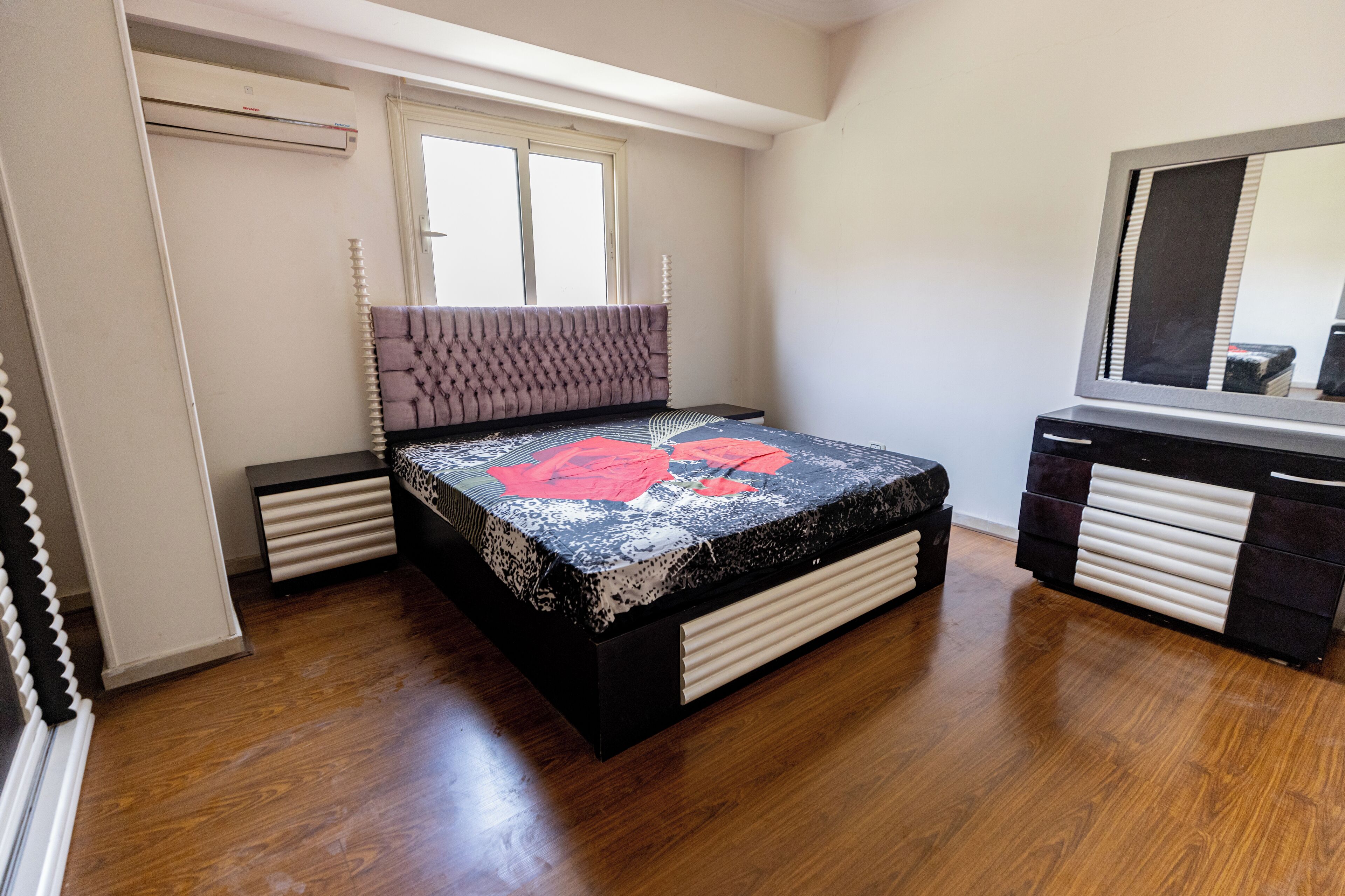 Une chambre à coucher avec un lit, une commode et un grand miroir.