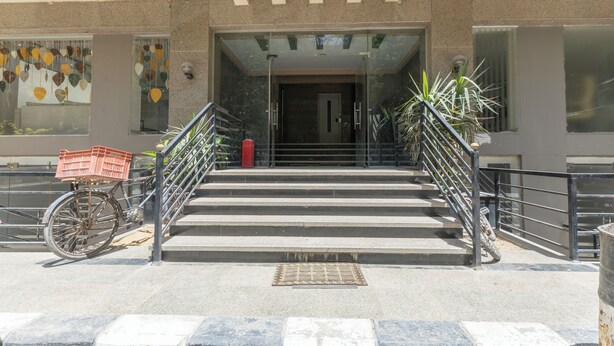 A building entrance with a staircase leading up to a door, a bicycle parked to the side, and a potted plant near the stairs. - Hibiscus Haven Suite  (Cairo)