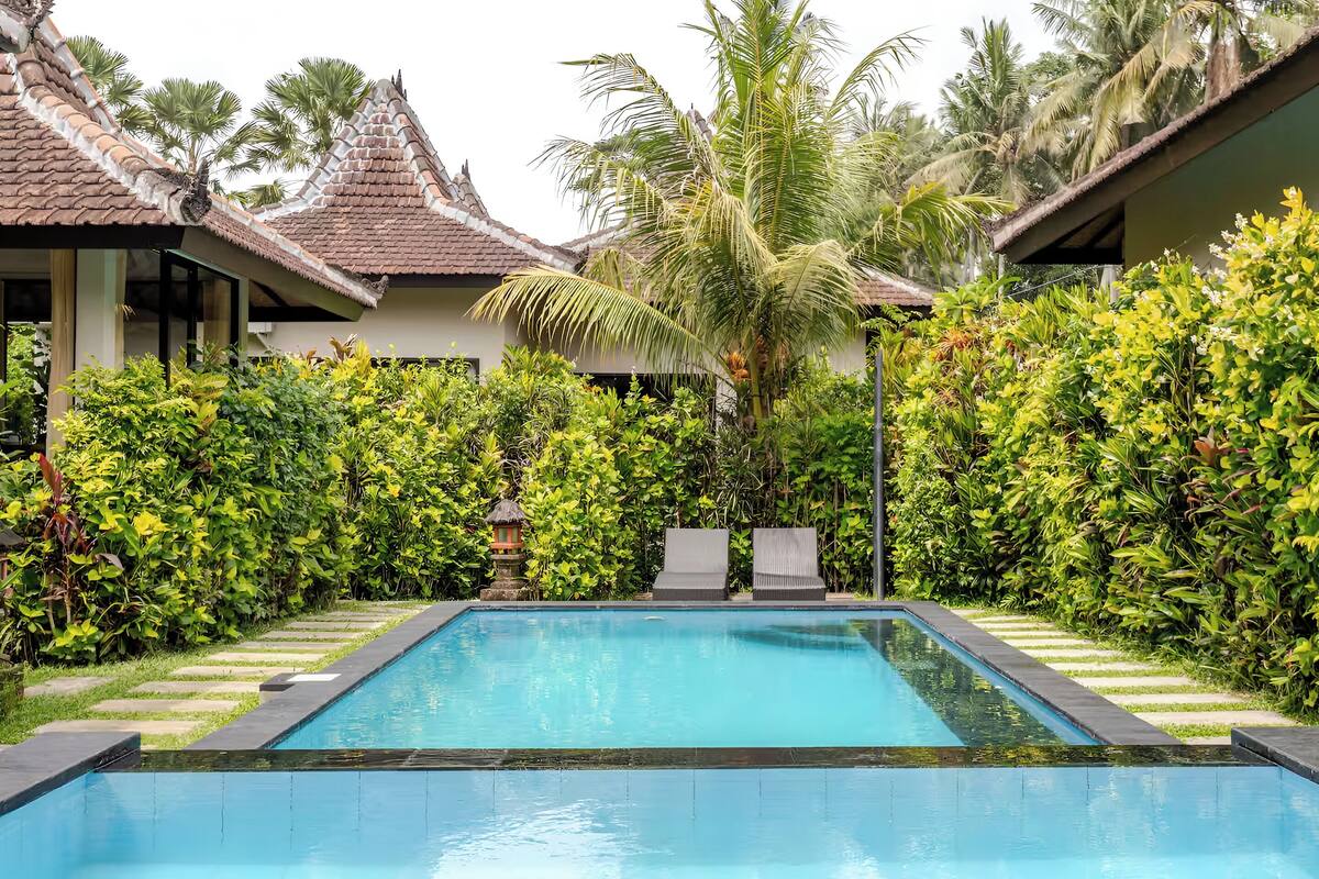 A swimming pool surrounded by lush greenery and traditional architecture.