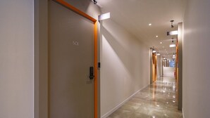 A modern hotel corridor with a clean, minimalist design, featuring a polished floor and bright lighting. - HOTEL YAM-GUMI (Gumi)
