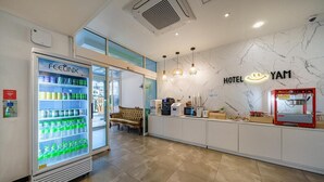A hotel reception area with a vending machine, a sofa, a coffee machine, and a wall with the hotel's name. - HOTEL YAM-GUMI (Gumi)