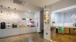 A hotel reception area with a marble wall, a reception desk, a microwave, a coffee machine, and a refrigerator. - HOTEL YAM-GUMI (Gumi)