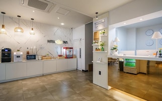 A hotel reception area with a marble wall, a reception desk, a microwave, a coffee machine, and a refrigerator.