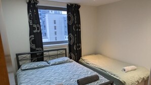 A bedroom with two beds, one larger and one smaller, both with neatly made linens. - Modern 2 bed apartment with stunning seaside view (Leith)
