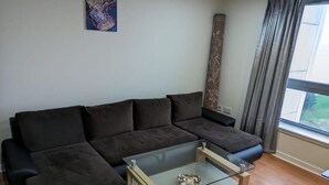 A modern living room with a sectional sofa, a glass coffee table, and a large window with curtains. - Modern 2 bed apartment with stunning seaside view (Leith)