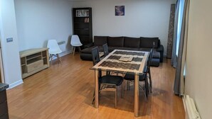 A living room with a dining table, sofa, and a bookshelf. - Modern 2 bed apartment with stunning seaside view (Leith)