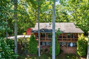 A cabin with a porch, surrounded by trees and a stone foundation. - On Mountain Time -Secluded 2 King BR, 2BA Log Cabin, HT, FP, VIEWS! (Waynesville)