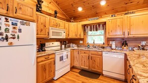 Una cocina tipo cabaña de madera con armarios de madera, refrigerador, microondas, estufa y lavavajillas.