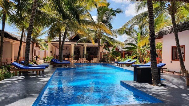A pool area with lounge chairs and palm trees.