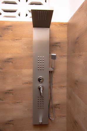 A modern shower with a control panel, a handheld showerhead, and a flexible hose.