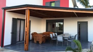 A covered patio area with a wooden bench and a table with chairs. - Profiter de L'extèrieur Avec Cette Villa (Saint-Louis)