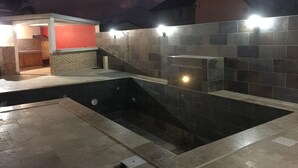 A swimming pool with a tiled deck and a small adjacent structure with a red wall. - Profiter de L'extèrieur Avec Cette Villa (Saint-Louis)