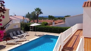 A swimming pool with lounge chairs and a view of the sea. - 3 Bedroom Villa, San Jaime, Son Bou (Son Bou)