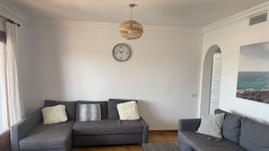A living room with two grey sofas, a wooden coffee table, and a wicker pendant light. - 3 Bedroom Villa, San Jaime, Son Bou (Son Bou)