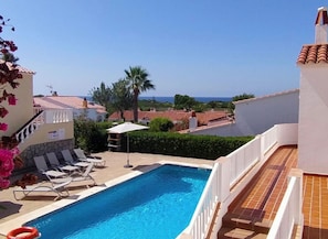 A swimming pool with lounge chairs and a view of the sea.