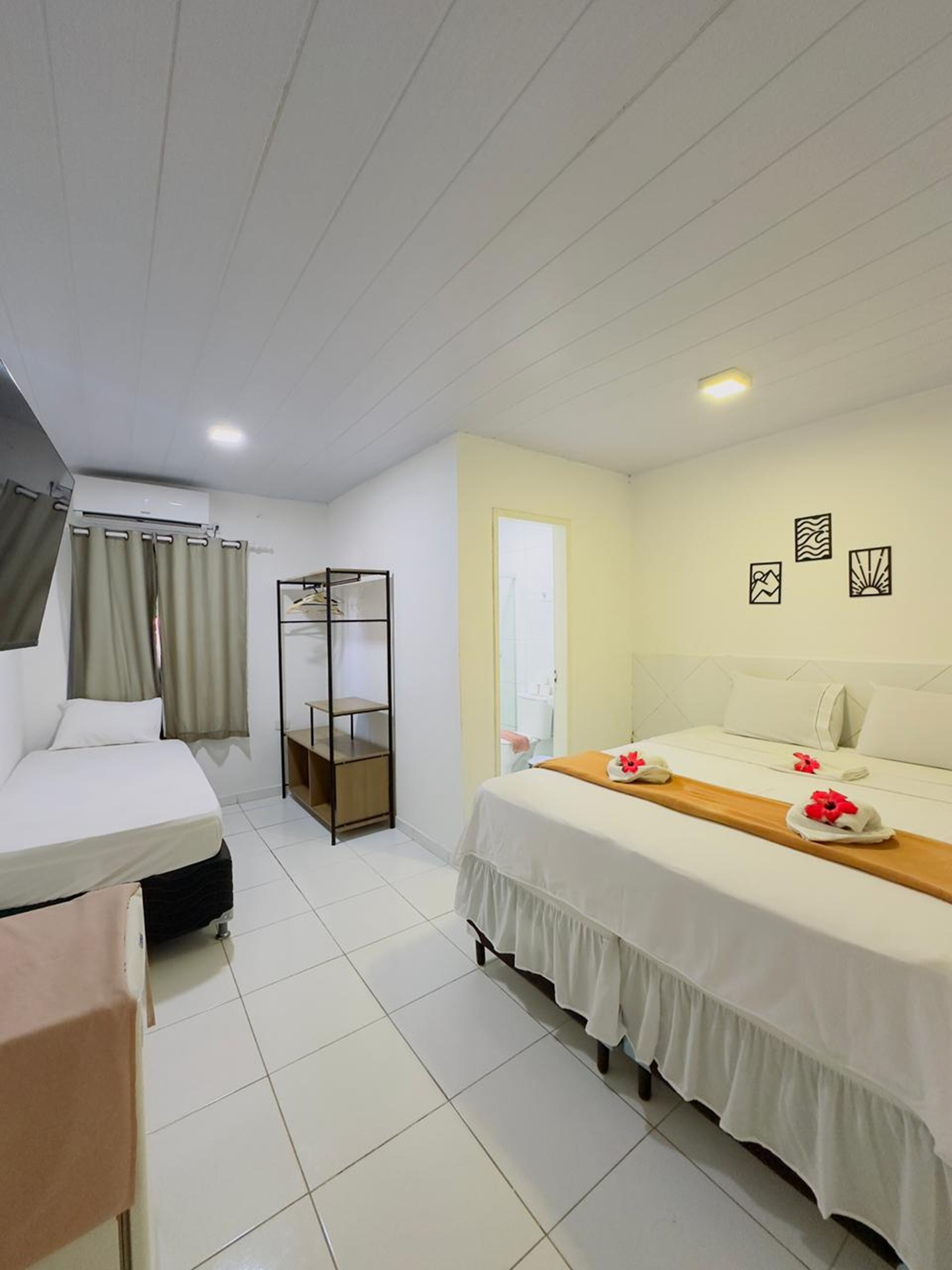 A hotel room with two beds, a wardrobe, a mirror, and a bathroom door.