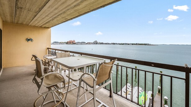 A balcony with a table and chairs overlooking a body of water.