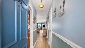 A hallway with blue doors, a wooden floor, and a hanging light fixture.