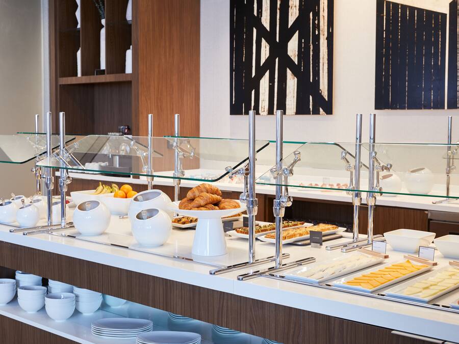 A buffet counter with various food items, including pastries and cheese.