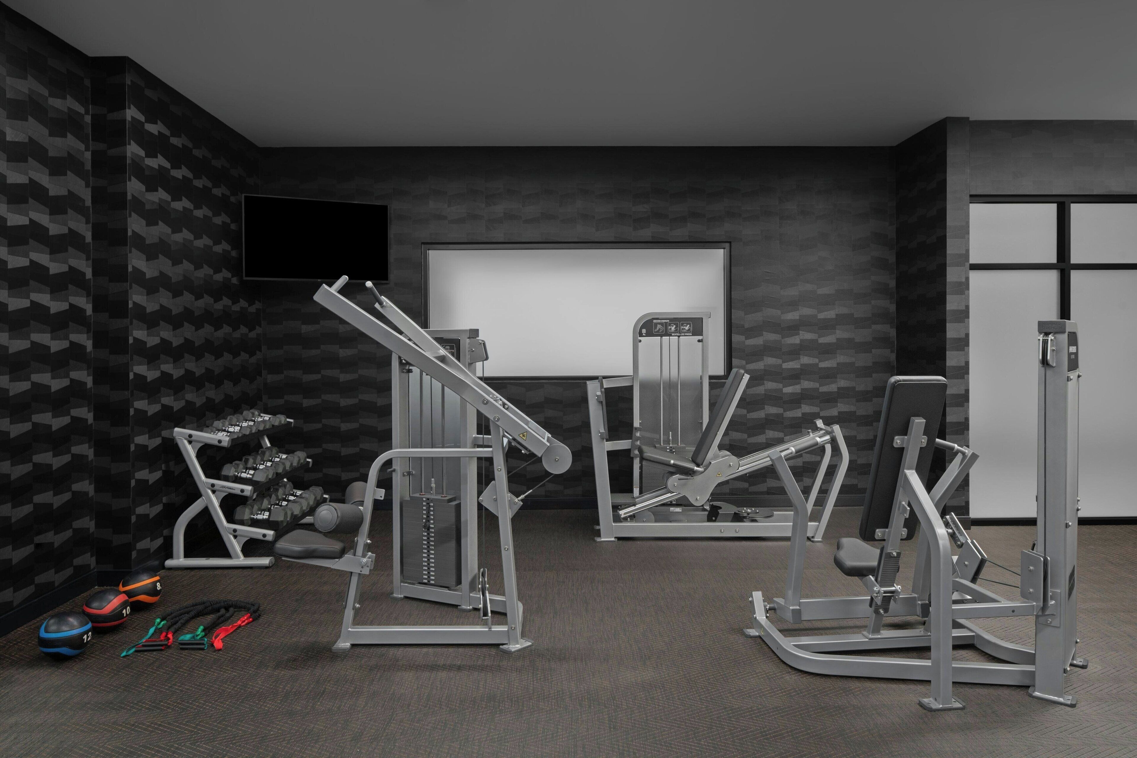 A gym with various exercise machines, dumbbells, and resistance bands.