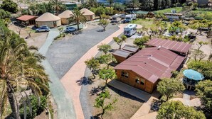 Eine Luftaufnahme eines Campingplatzes mit Jurten, Wohnmobilen und einem großen Gebäude mit der Aufschrift 'PABELLON POLIDEPORTIVO MUNICIPAL'.