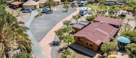 An aerial view of a campsite with yurts, RVs, and a large building labeled "PABELLON POLIDEPORTIVO MUNICIPAL."