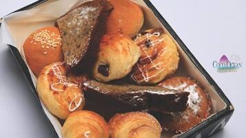 Una caja de pasteles variados, incluyendo croissants, un éclair de chocolate y un bollo glaseado.