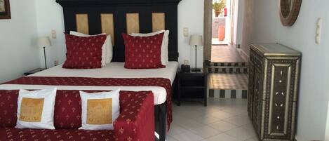 Een hotelkamer met een groot bed, twee nachtkastjes, een dressoir en een spiegel aan de muur.
