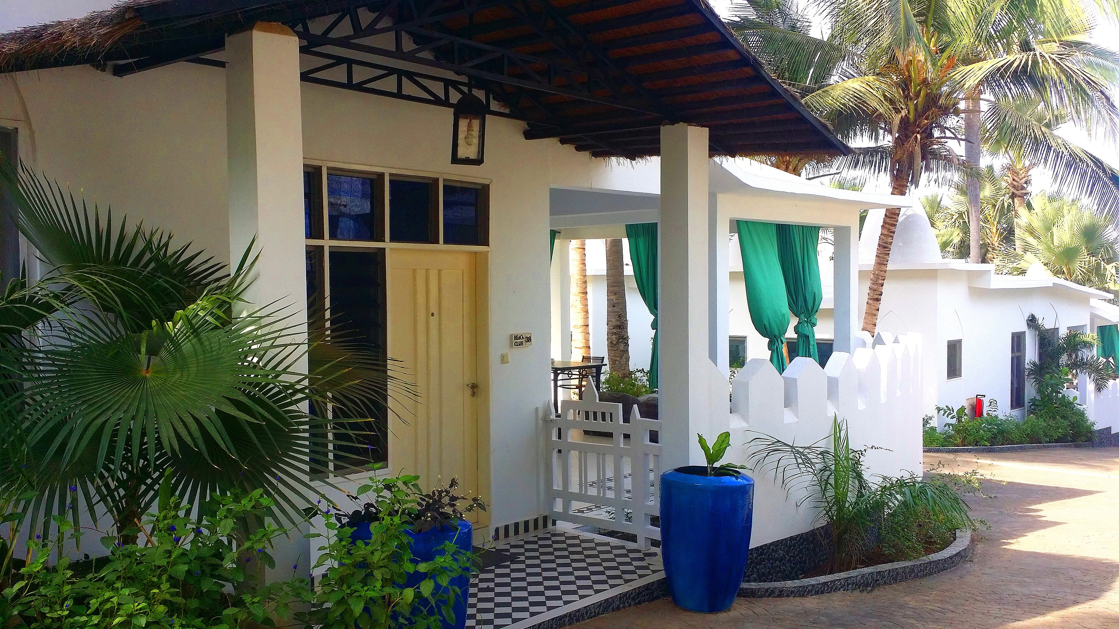 A building with a white facade, a wooden door, and a balcony with a white railing.