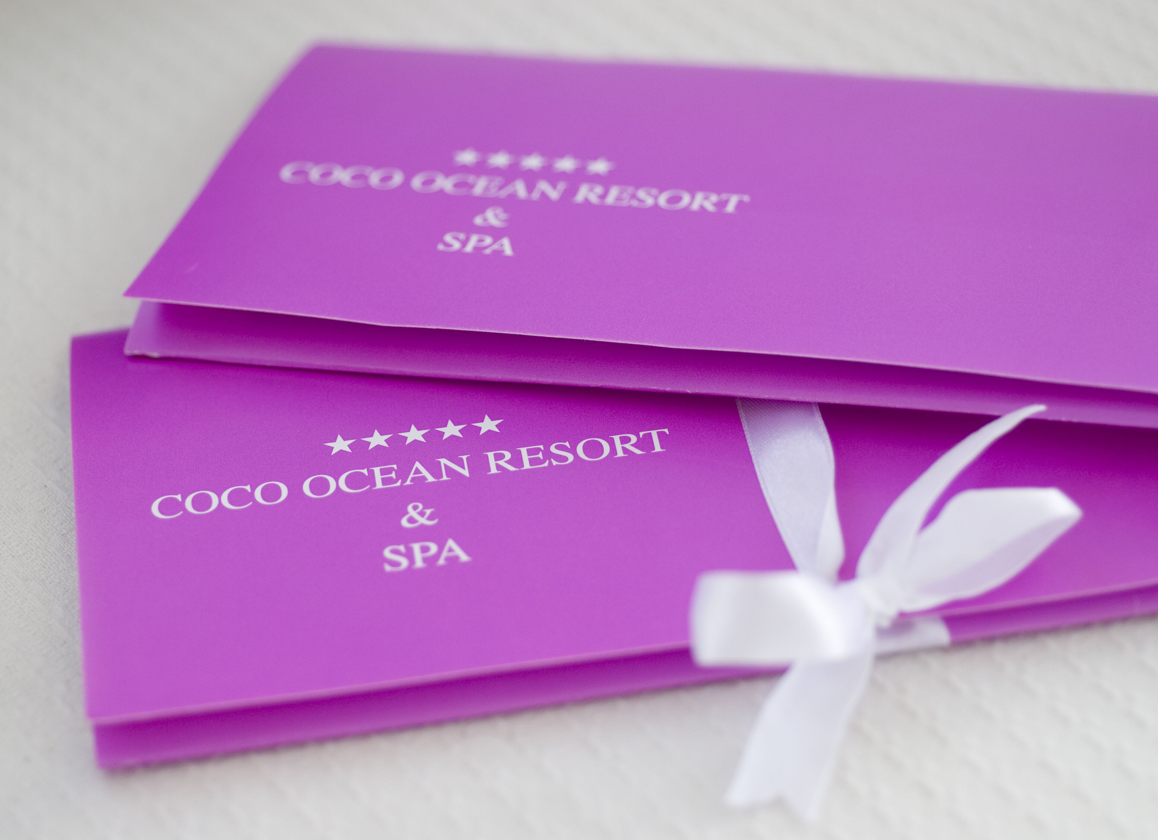 Two purple cards with the text "COCO OCEAN RESORT & SPA" and a white ribbon.