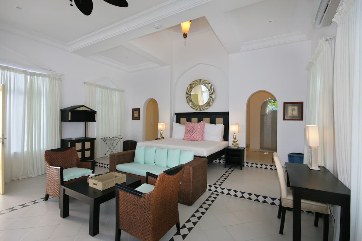 A hotel room with a bed, two sofas, a small table, and a desk.