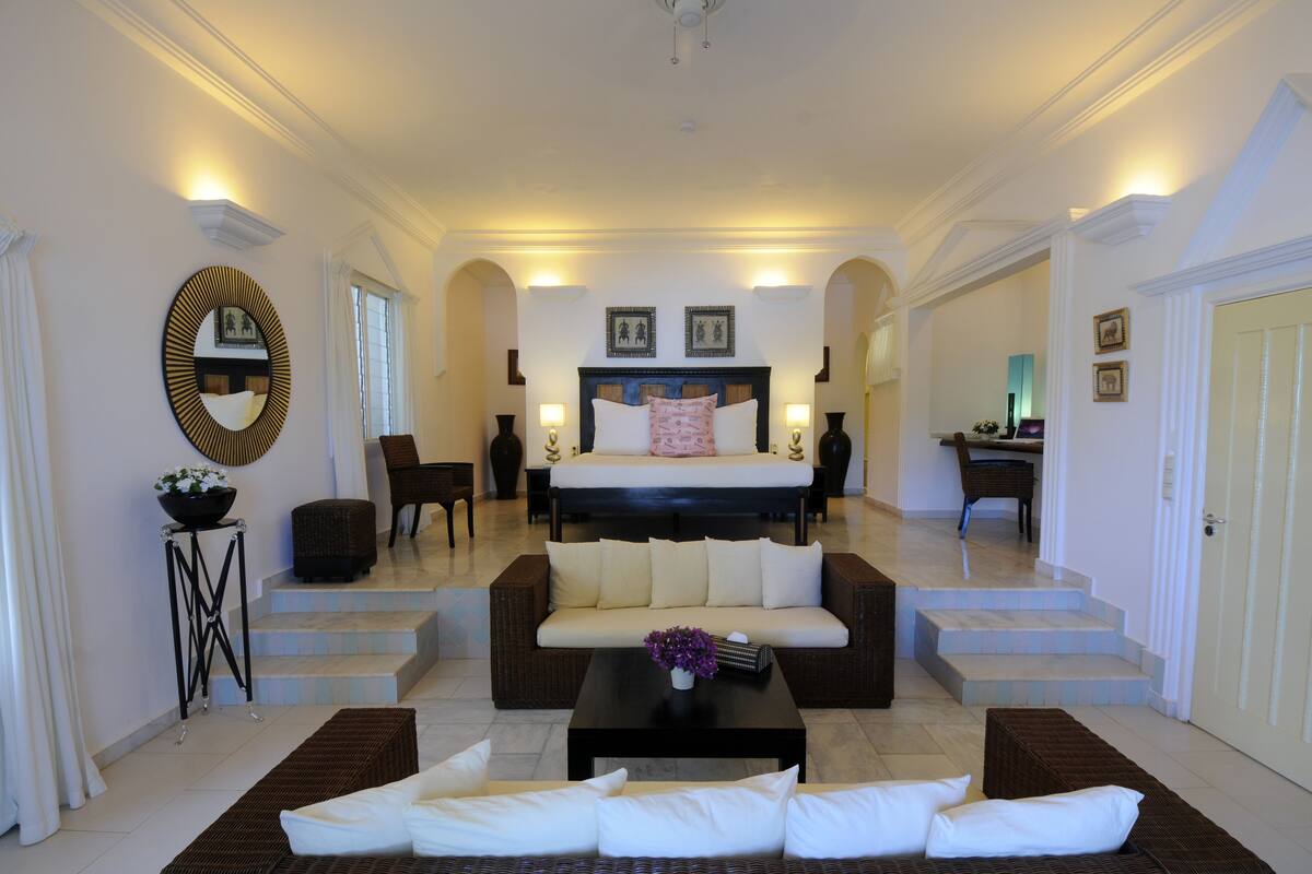 A spacious living area with a sofa, coffee table, and a bed with a headboard.