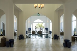 Un vestíbulo amplio con piscina central, techos altos y ventanas grandes.