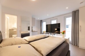 Ein modernes Hotelzimmer mit einem großen Bett, einem Flachbildfernseher und einem durch eine offene Tür einsehbarer Badezimmer.