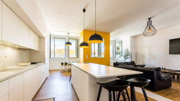 Ett modernt kök med en central köksö, barstolar och en matplats med en soffa och ett soffbord.