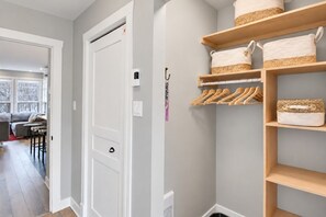 A hallway with a white door, a coat rack with hangers, and a shelf with baskets. - Tremblant Prestige - Les Eaux 207-2 (Mont-Tremblant)