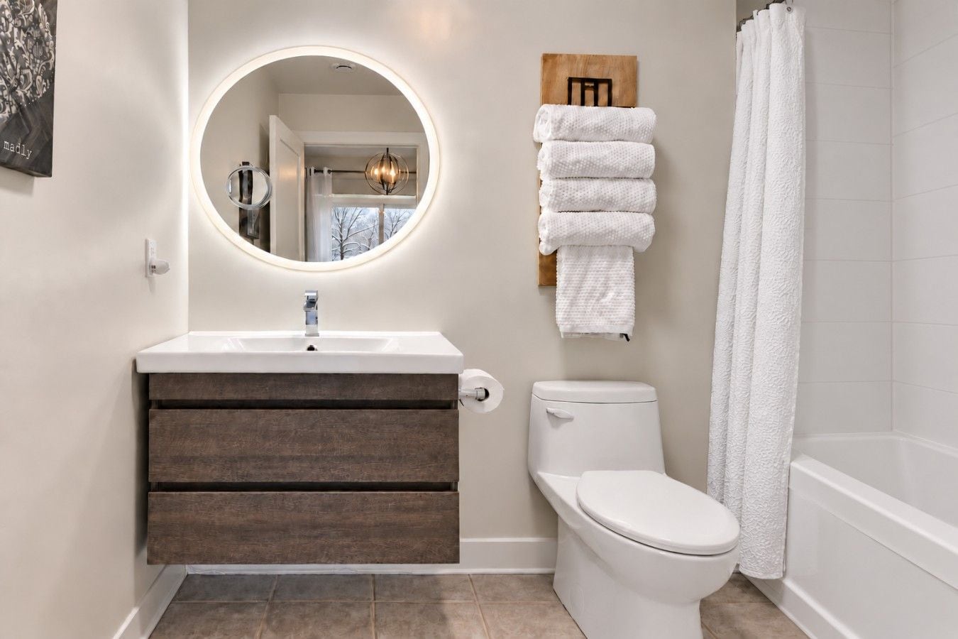 Een badkamer met een ronde spiegel, een wastafel, een toilet en een bad.