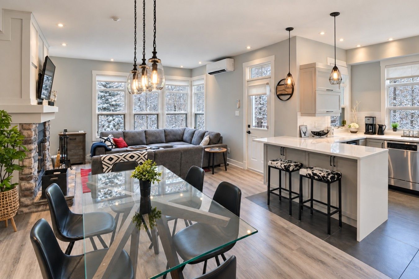 A modern kitchen with a central island, bar stools, and a dining area with a glass table and chairs.