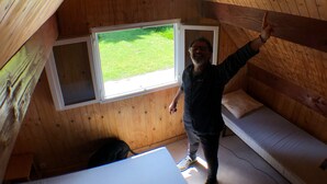 Ein kleiner, holzgetäfelter Dachzimmer mit geneigter Decke, einem Fenster und einem Bett.