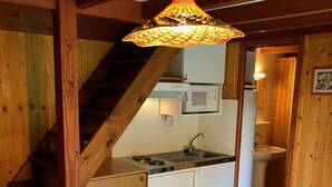 Eine Küche mit einer Holztreppe, einem Esstisch mit Obstschale und einer Hängelampe.