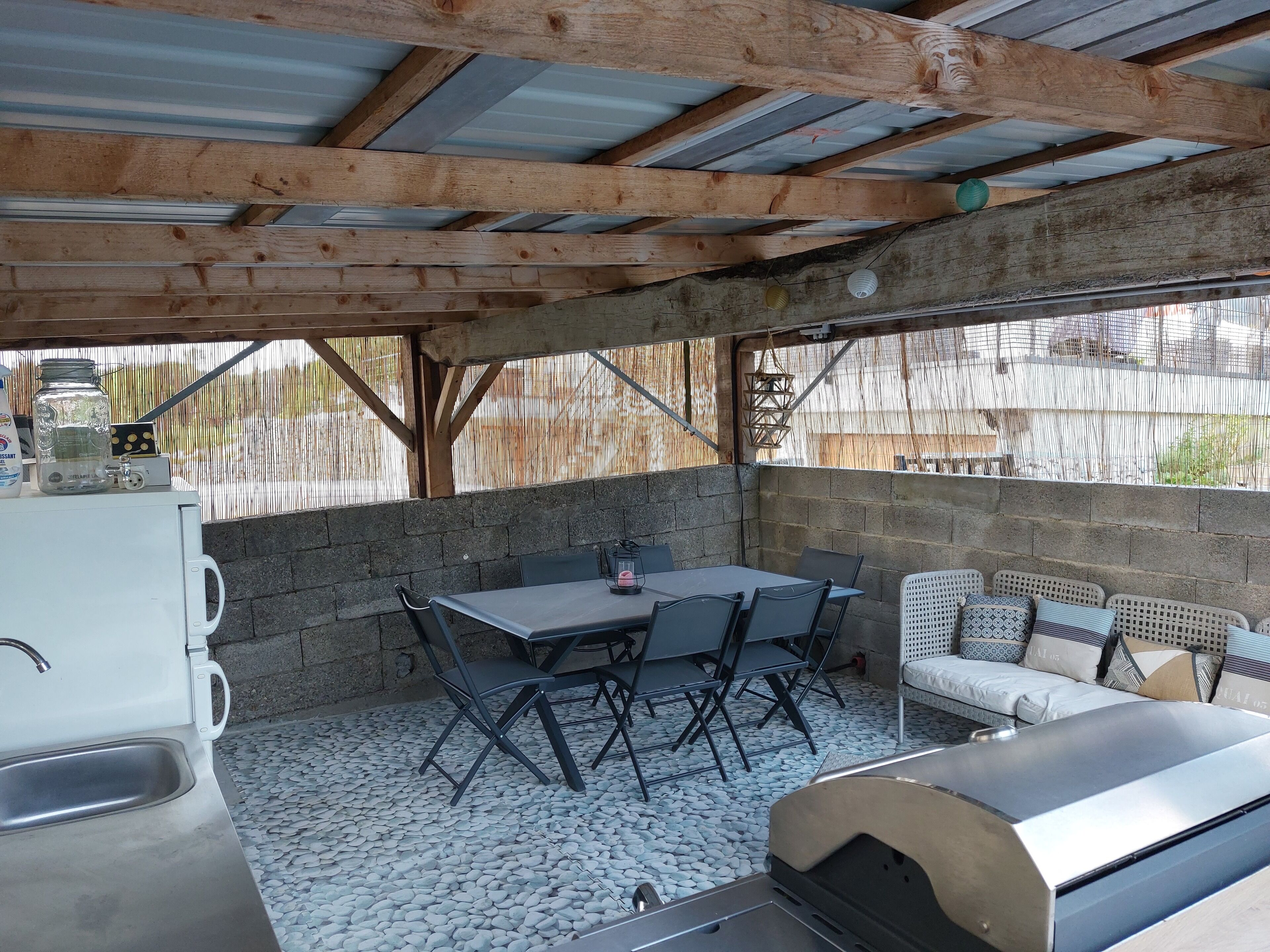 An outdoor patio with a grill, seating area, and a white refrigerator.