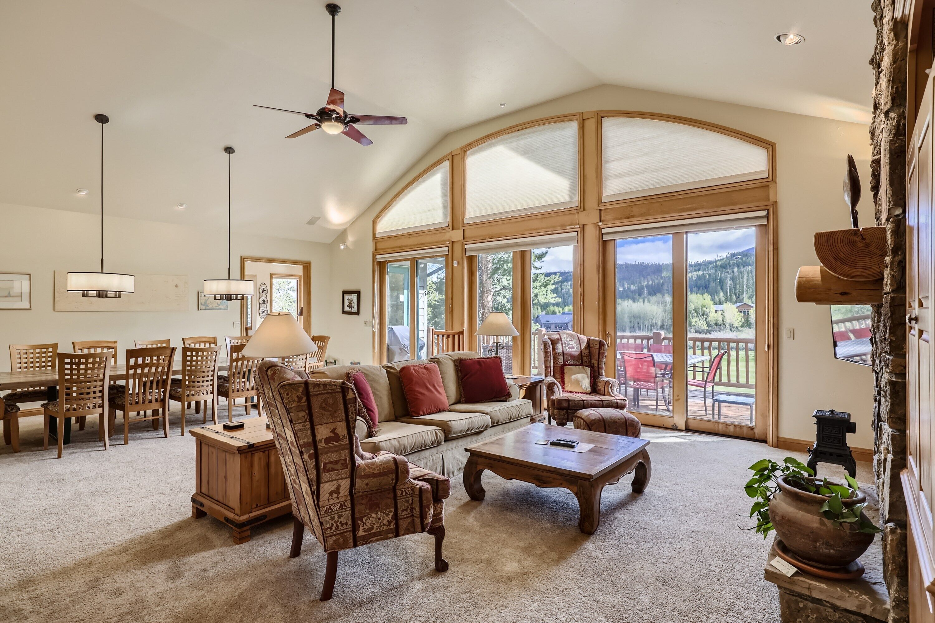 A spacious living room with a high ceiling, large windows, and a cozy seating area.