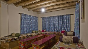A traditional room with a wooden ceiling, a long wooden table, and patterned cushions. -  Pangong Retreat Camp (Leh)